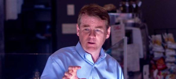 Michael Bennet speaking to patrons inside of a store.