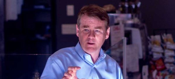 Michael Bennet speaking to patrons inside of a store.